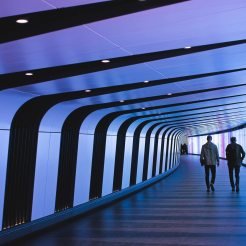 Two people walking in futuristic tunnel