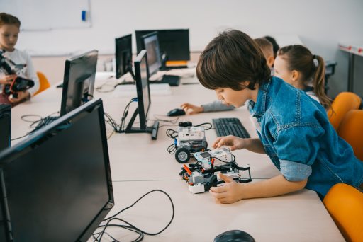 Child playing with robot next to computers